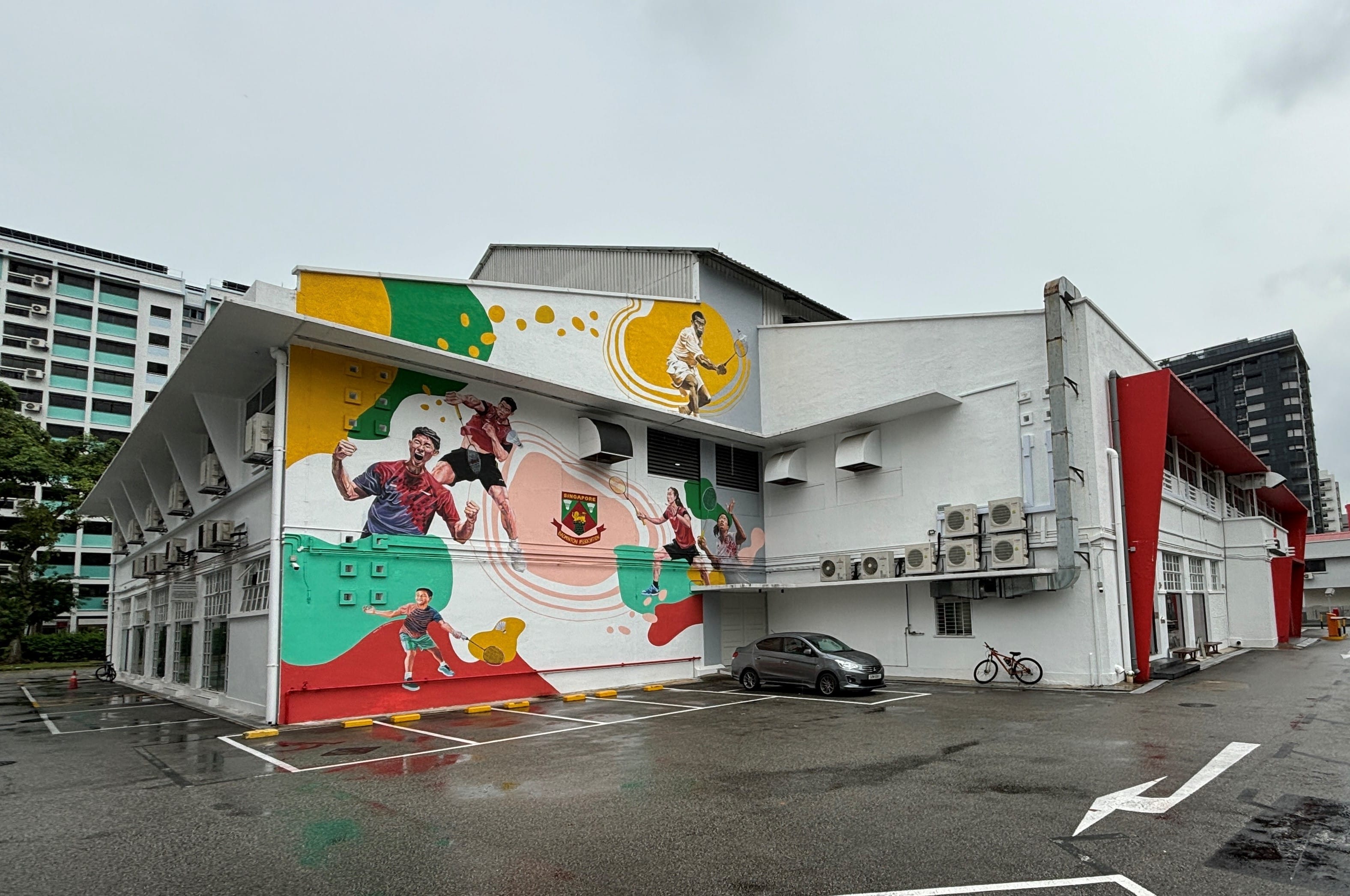 Building with a colorful mural of badminton players and the Singapore Badminton Association logo.